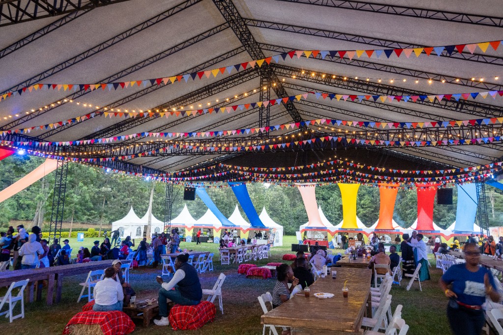 Evening gathering under a lit marquee tent with communal tables at HereAfrica