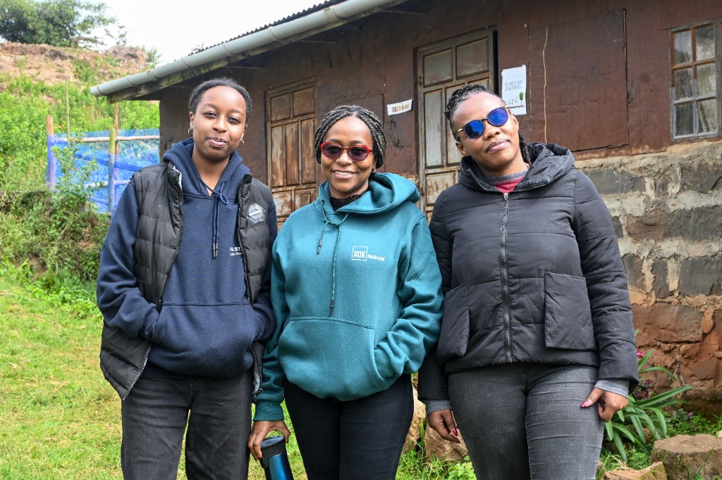 Three women standing in front of the seed bank building at the living lab